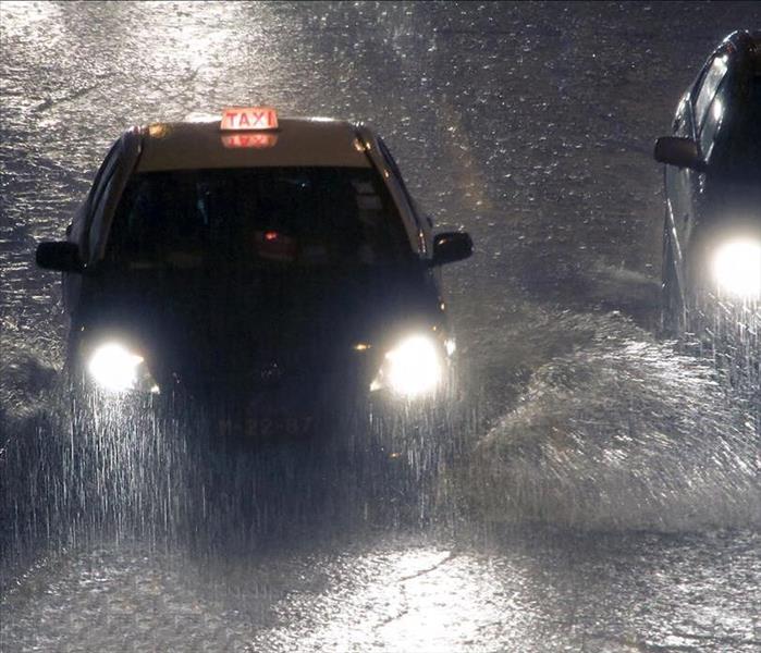 Cars driving thru heavy rain at night.